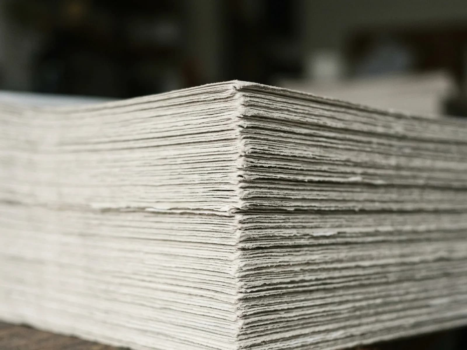 Close detail of the corner of a tall stack of rough paper sheets.